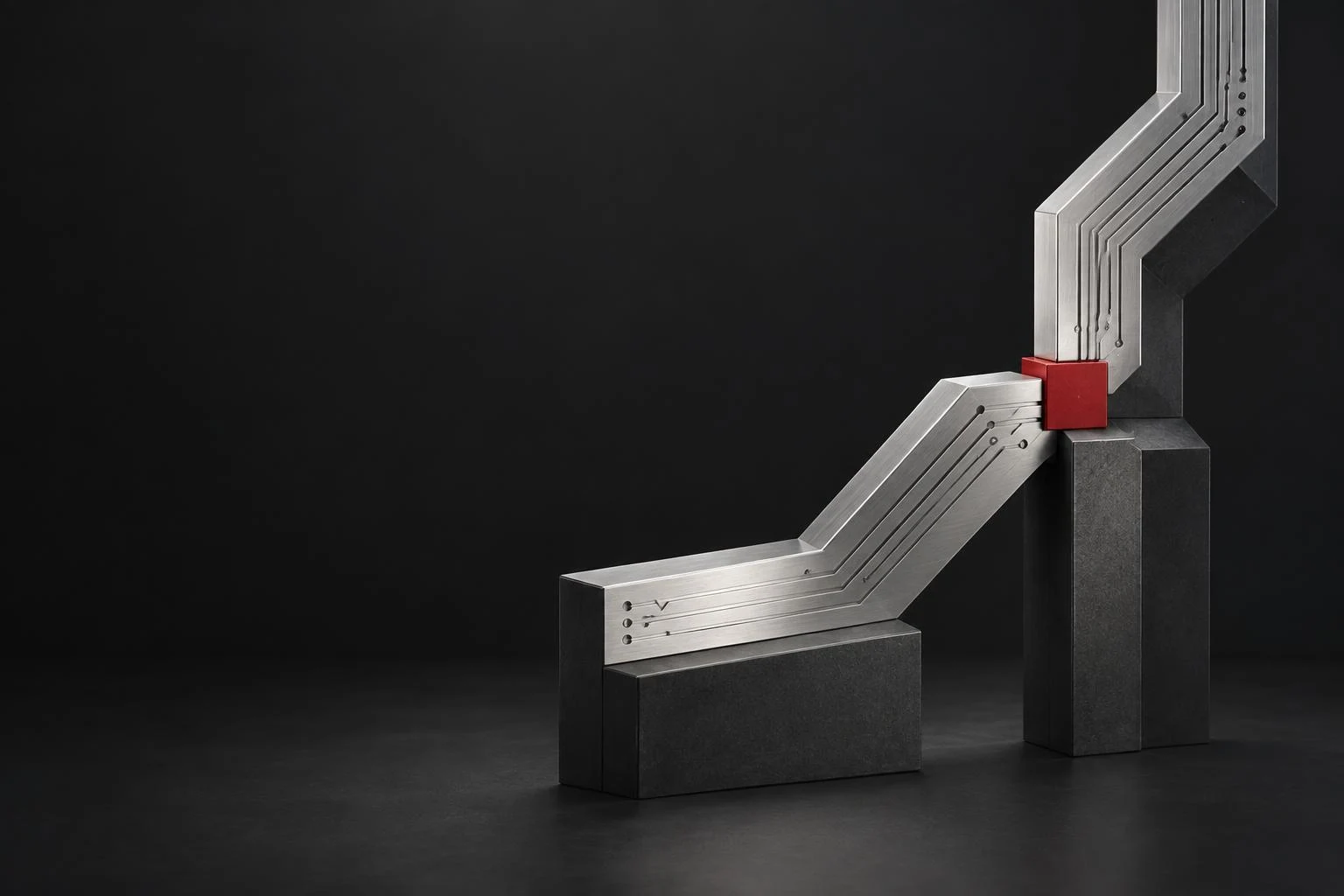 Two machined silver circuit pathways meeting at a red contact point
